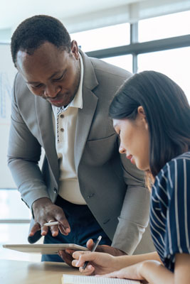 black male professor consults with female colleague at table